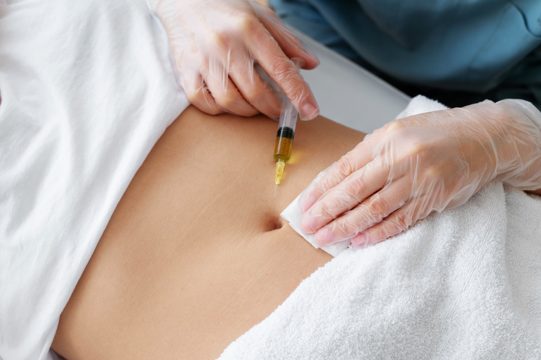 High angle healthcare professional injecting belly