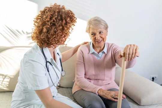 Friendly relationship between smiling caregiver in uniform and happy elderly woman supportive young nurse looking at senior woman young caring lovely caregiver and happy ward