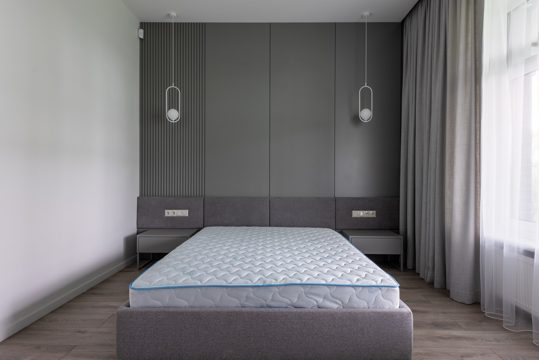 Comfortable bed with convenient modern mattress in contemporary interior of spacious gray bedroom