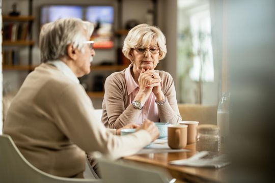 Mature couple thinking of something during breakfast time at home focus is on pensive woman