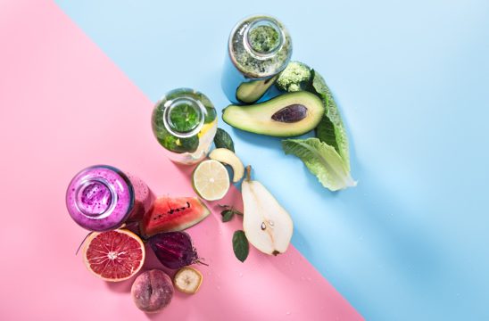 Glass bottles with natural drinks on a colored wall