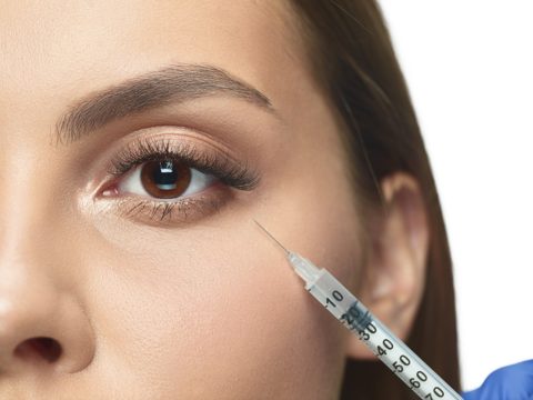 Close-up portrait of young woman isolated on white studio wall in filling surgery procedure