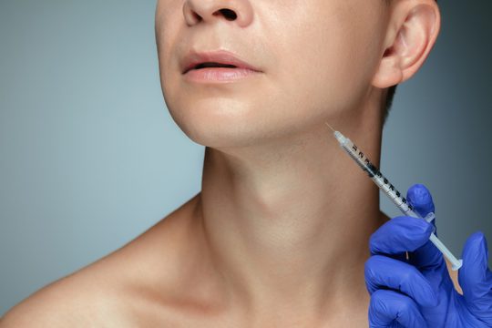 Close-up portrait of young man isolated on grey studio wall in filling surgery procedure