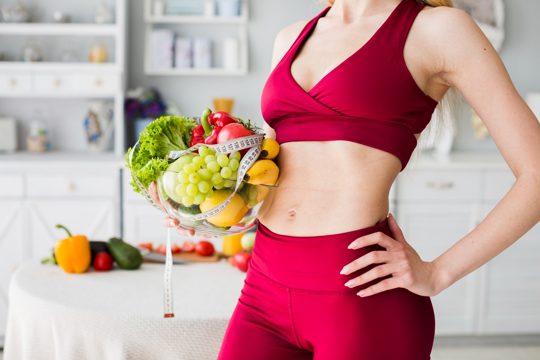 Diet concept with sporty woman in kitchen